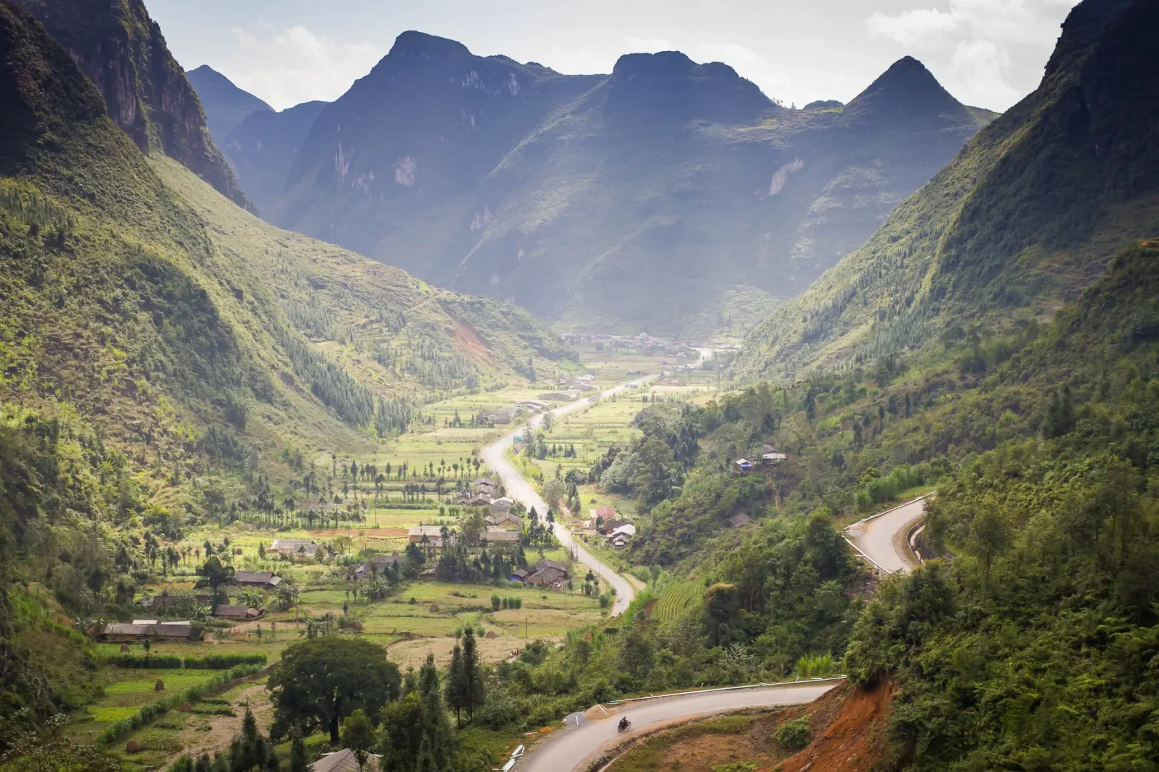 Eine Straße windet sich an den Hängen eines tiefen Tals in den Bergen von Ha Giang.