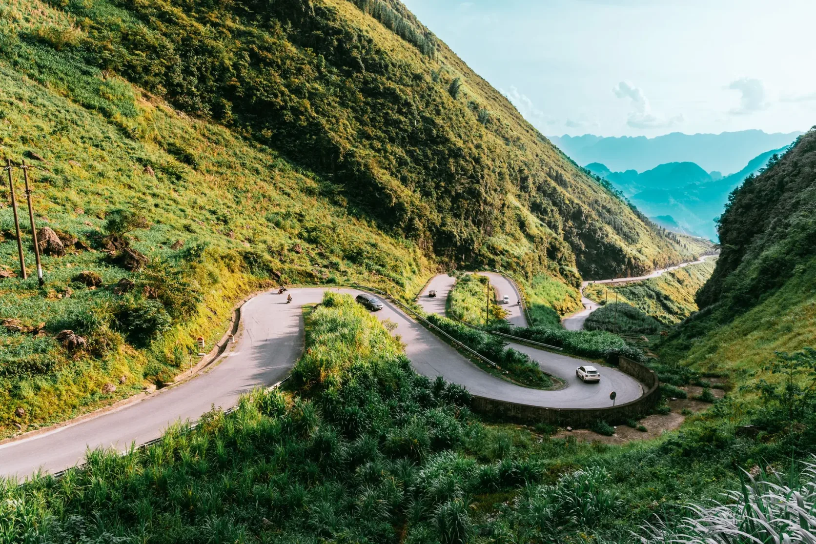Una carretera con curvas cerradas en una ladera verde de Ha Giang.