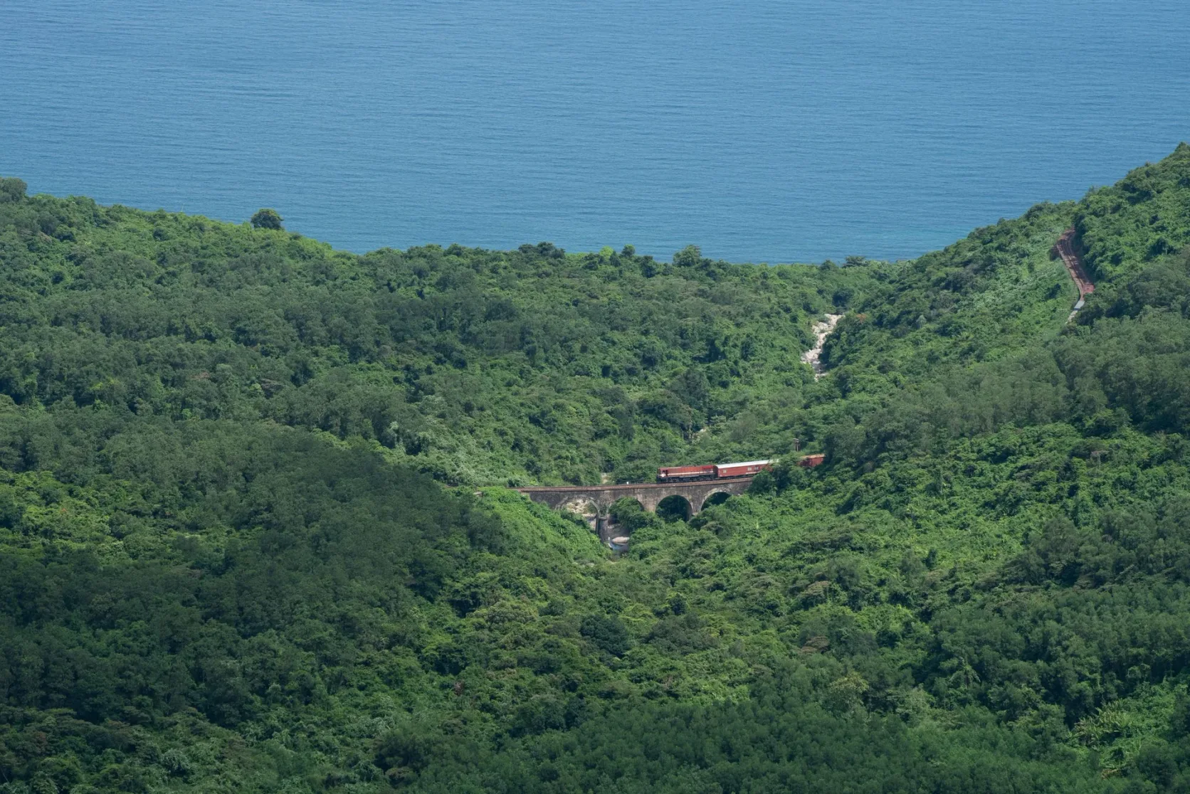 A passenger train above the sea on the Hải Vân stretch between Huế and Đà Nẵng.