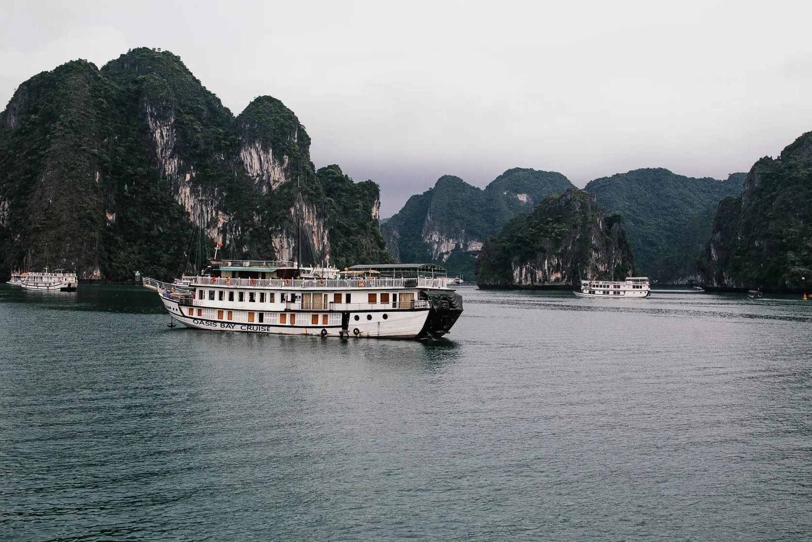 Kreuzfahrtboote zwischen den Kalksteininseln der Halong-Bucht bei Tag.