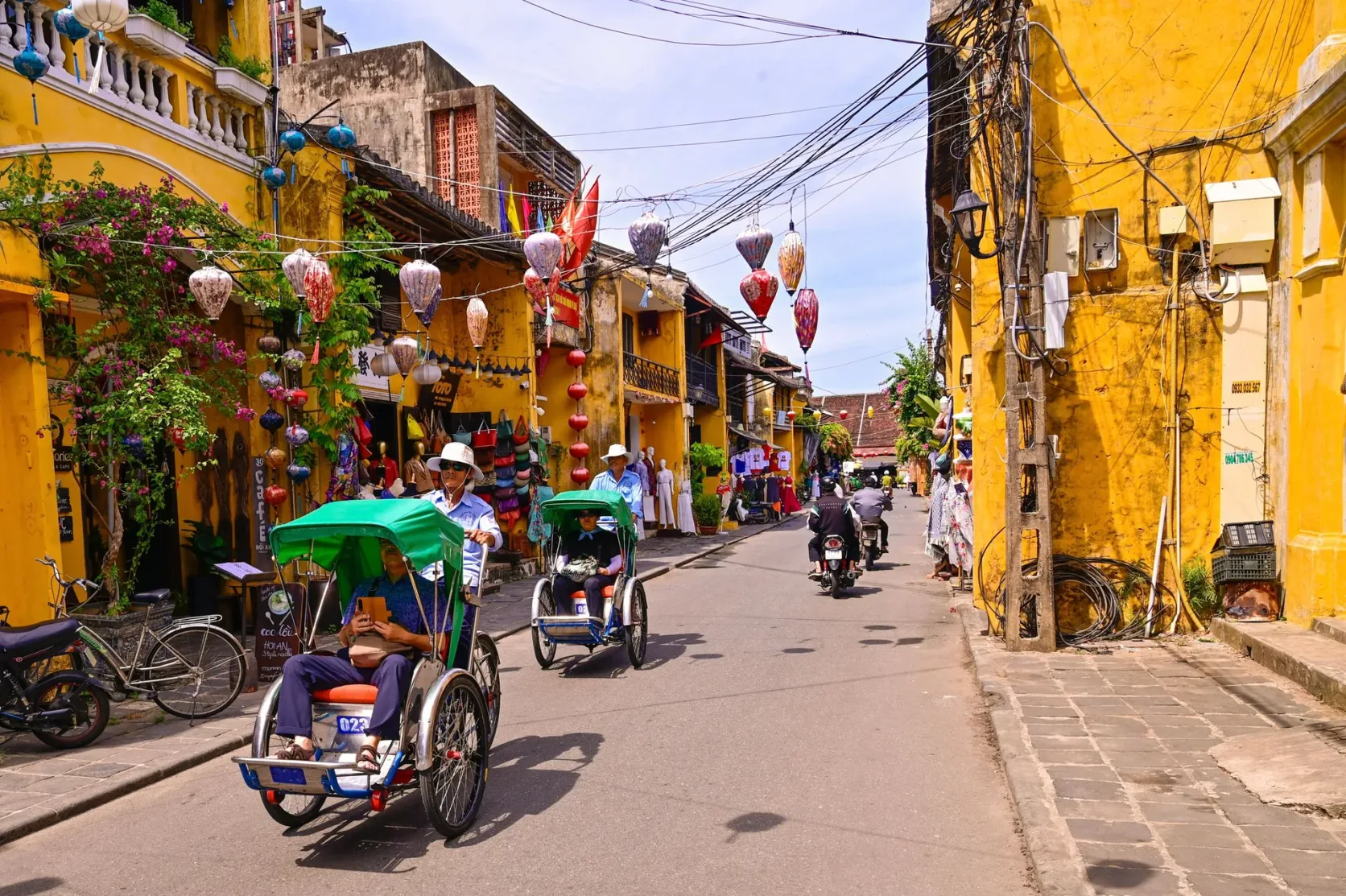 Des cyclo-pousses dans une rue de maisons jaunes de la vieille ville de Hoi An.
