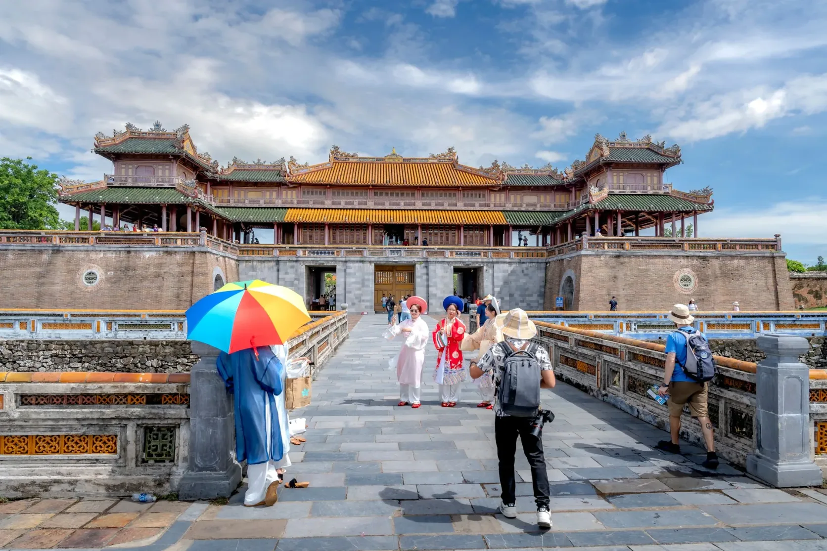 Besucher gehen auf ein Tor der Zitadelle von Huế zu.