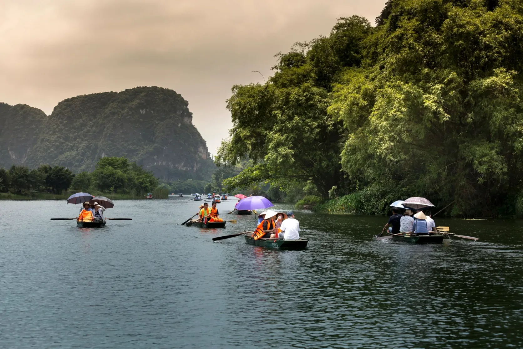 Ruderboote auf dem Wasser zwischen Kalksteinhügeln in Trang An.