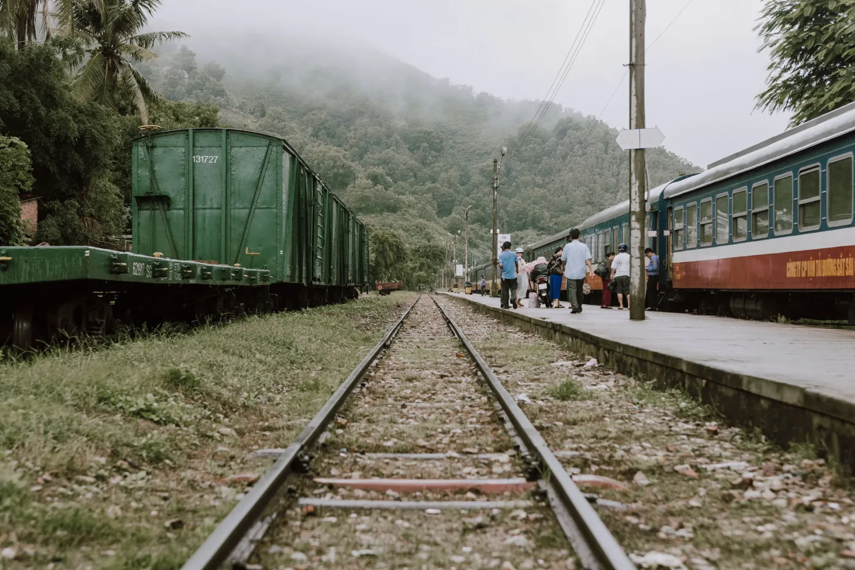 Un tren junto a un andén con niebla entre colinas kársticas.