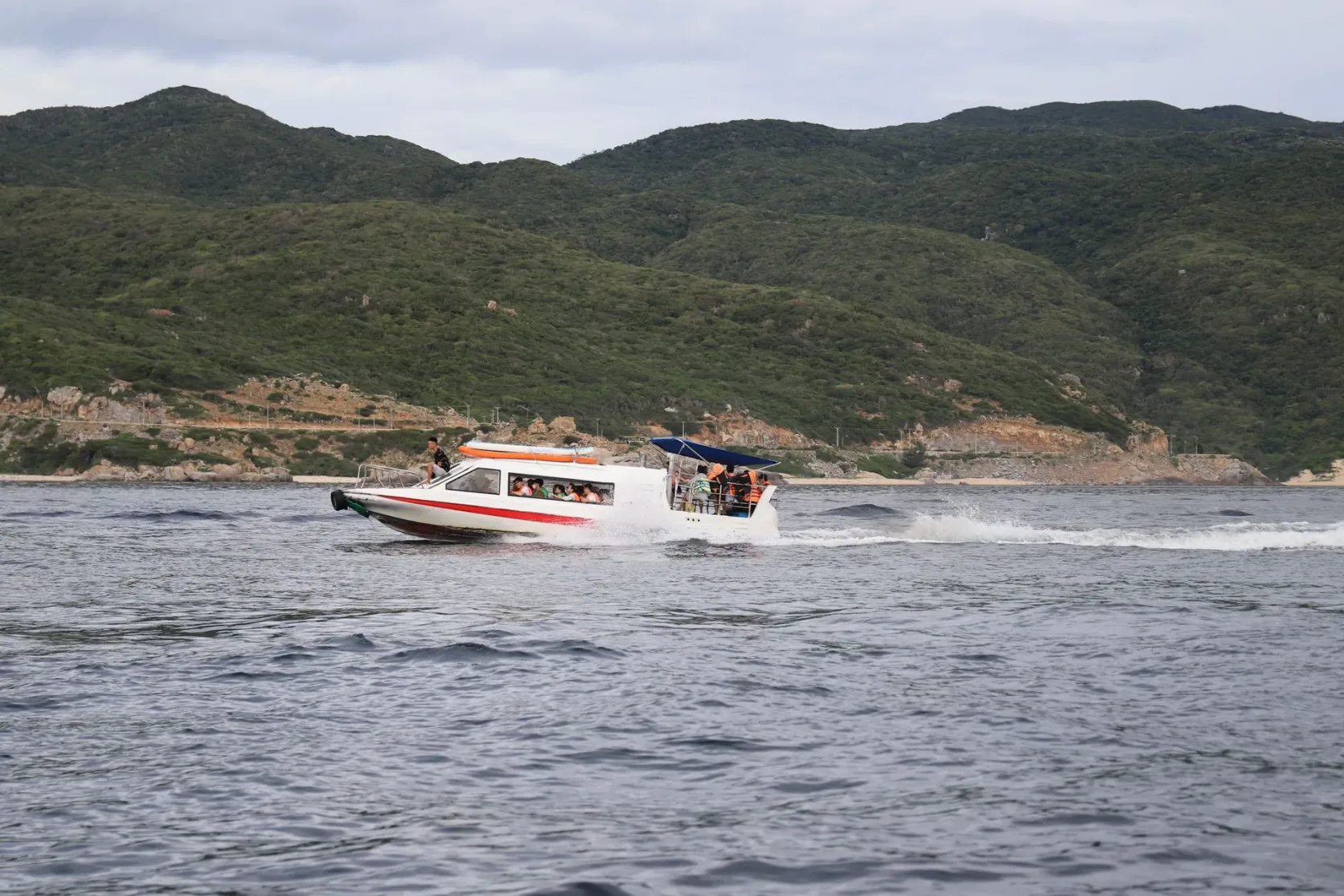 A speedboat running past green islands.